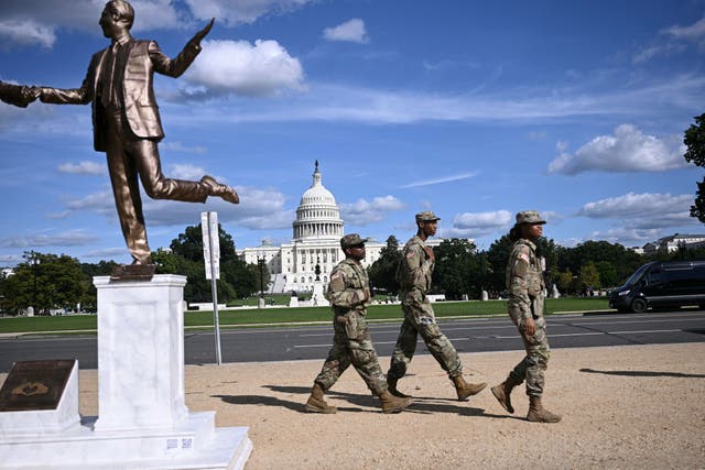 <p>Members of the National Guard patrol the National Mall in Washington, DC, next to a statue depicting US President Donald Trump and Jeffrey Epstein holding hands near the US Capitol on October 2, 2025</p>