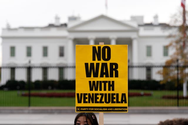 <p>A protester carries a sign opposing a U.S. war with Venezuela outside the White House in Washington, D.C. on November 15, 2025</p>