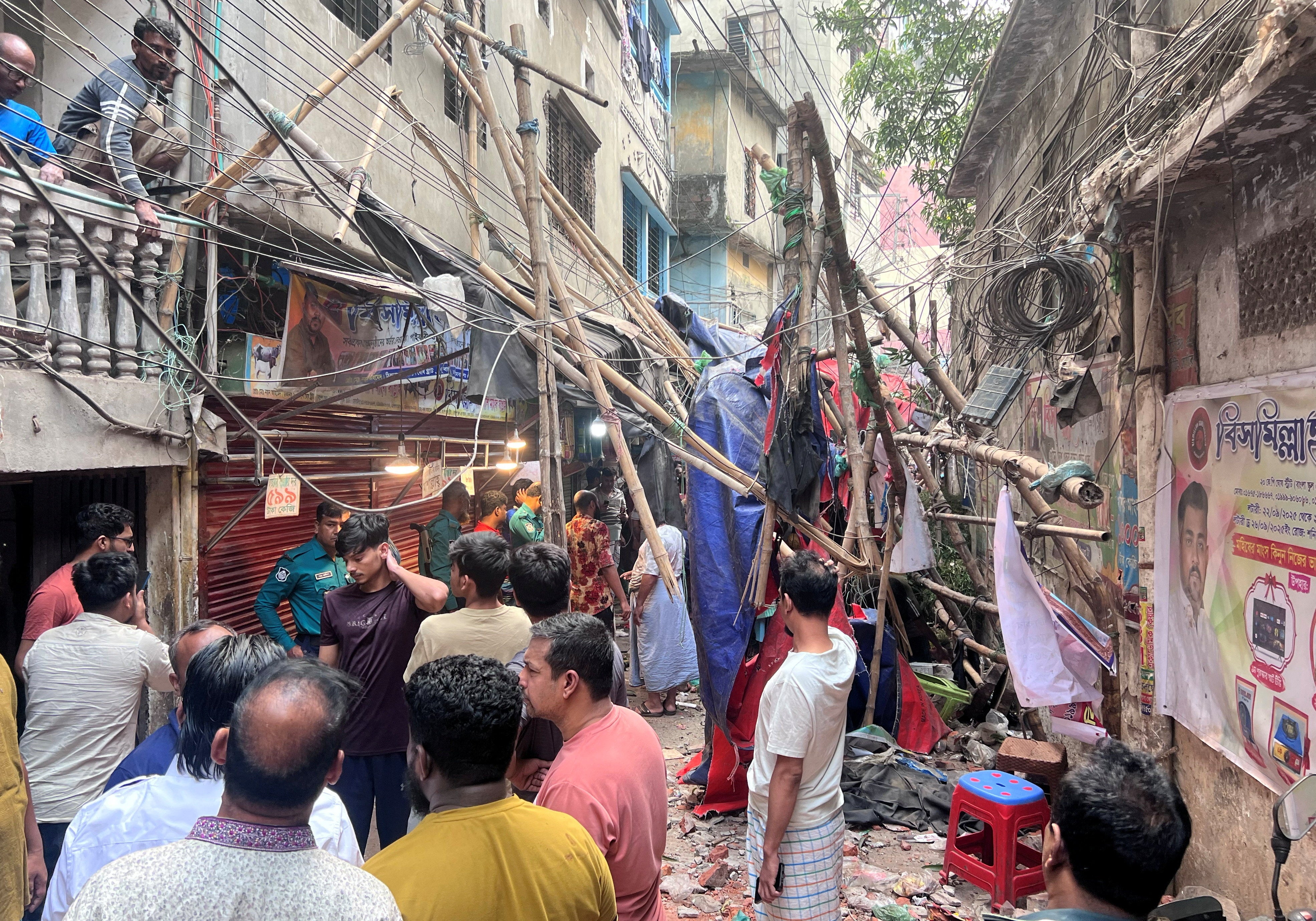 People stand in an alley after vacating their homes following an earthquake in Dhaka