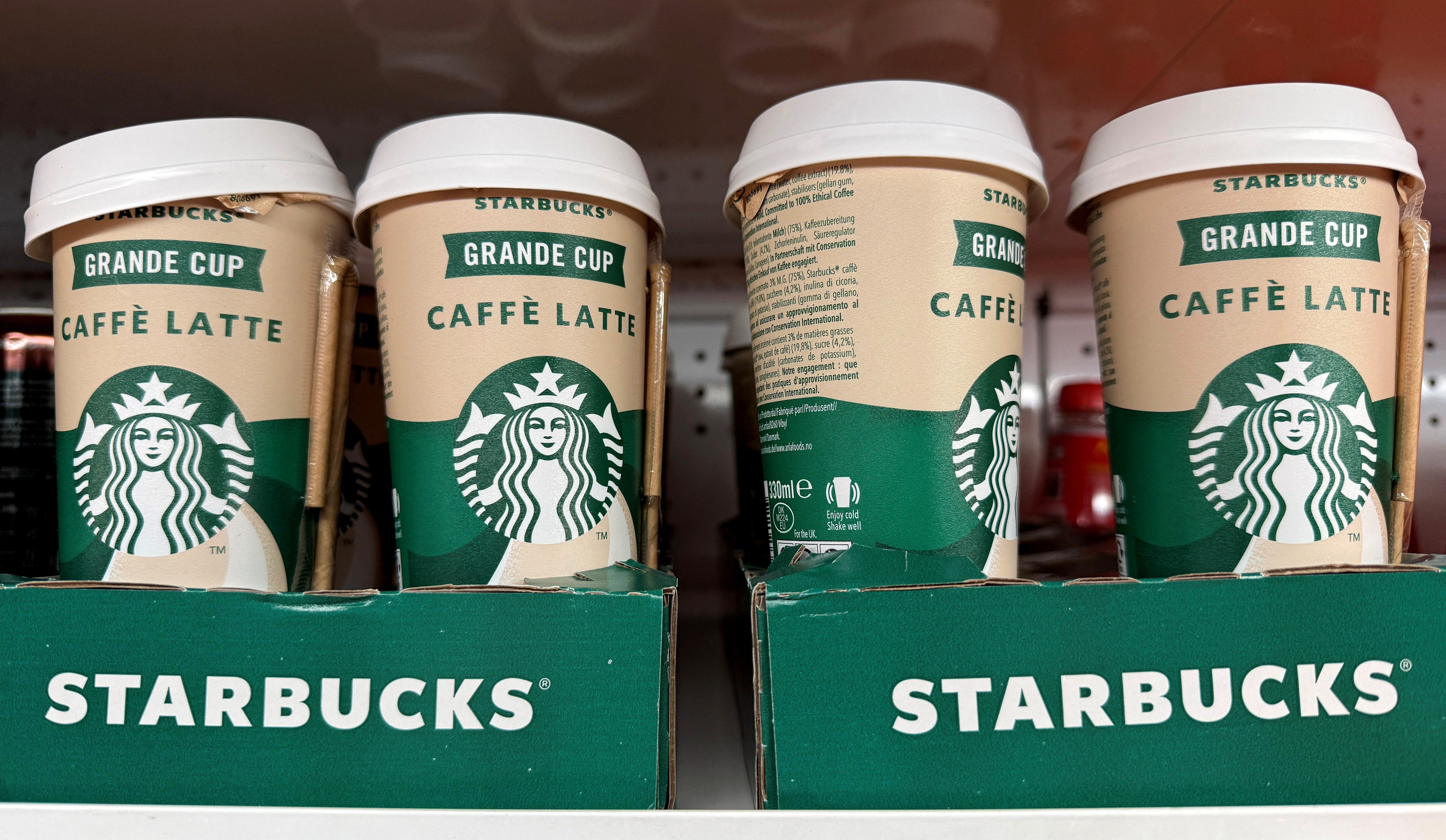 Cups of pre-made Starbucks iced latte drinks are lined up for sale on the shelf of a supermarket.