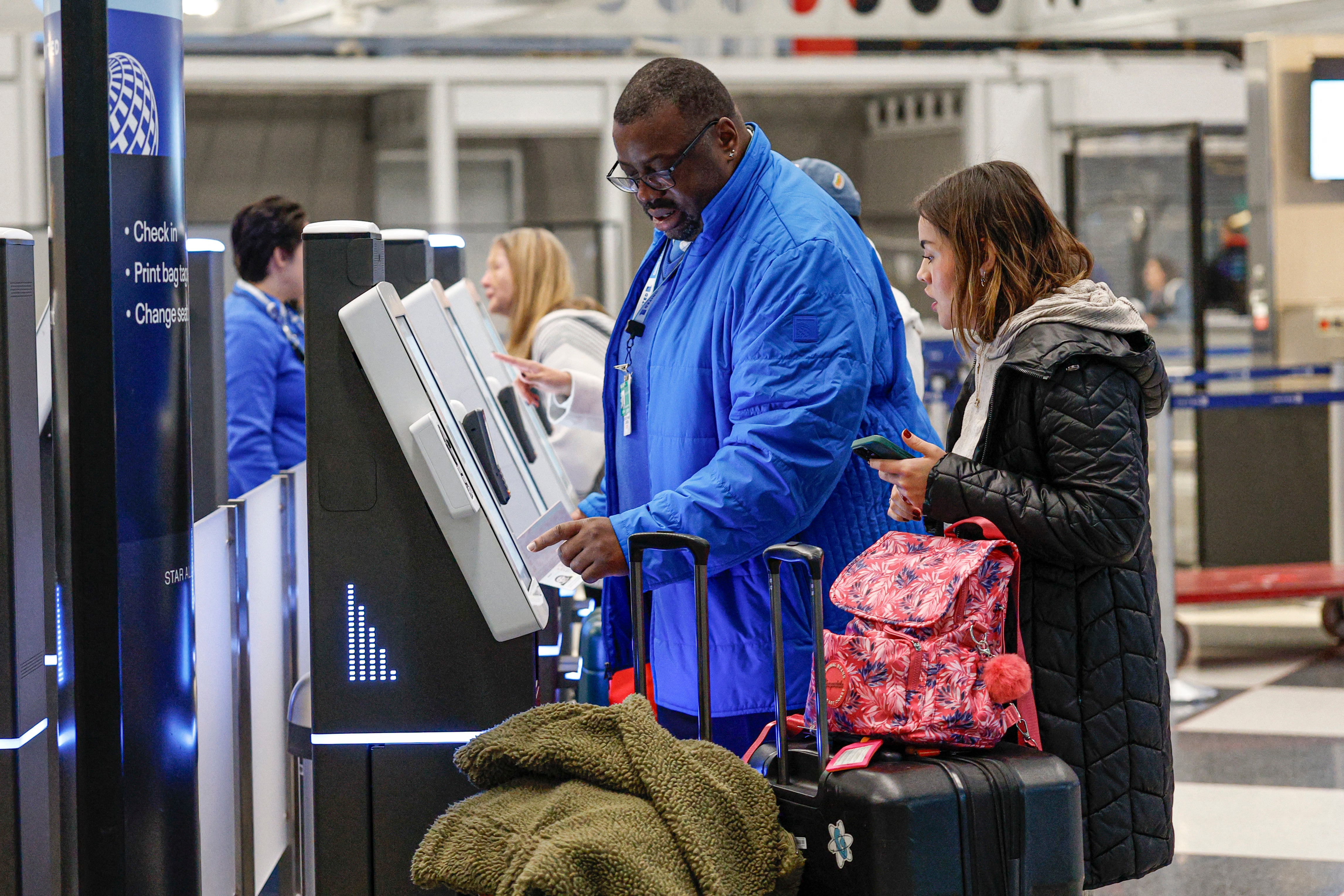 A United Airlines agent assists a traveler at O'Hare International Airport in Chicago, Illinois, on Tuesday, November 25, 2025