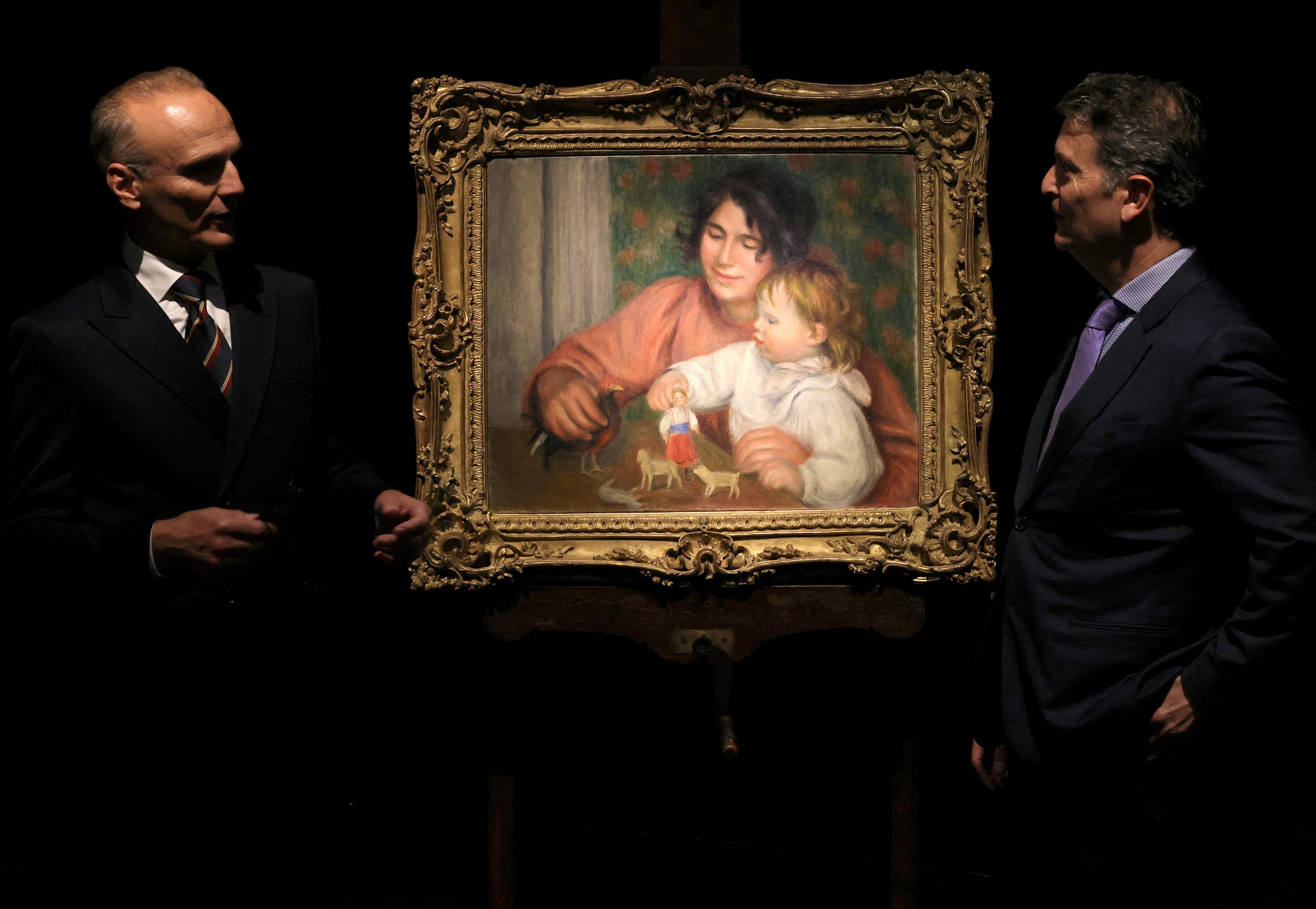 Auctioneer Christophe Joron-Derem and Art consultant Pascal Perrin stand next to the painting "L'enfant et ses jouets - Gabrielle et le fils de l'artiste, Jean" (Child with Toys - Gabrielle and the Artist's Son, Jean), before 1910, by artist Pierre-Auguste Renoir (1841-1919) on display before its auction at Drouot auction house in Paris, France