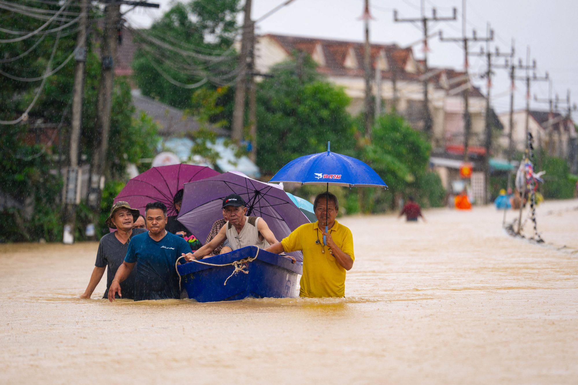 People wade through flood waters with residents being evacuated on a boat in Hat Yai in Thailand's southern Songkhla province