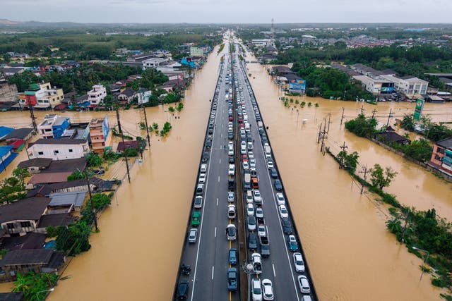 <p>Vehicles are parked on an elevated road to keep them out of floodwaters in Hat Yai, Songkhla province, Thailand</p>