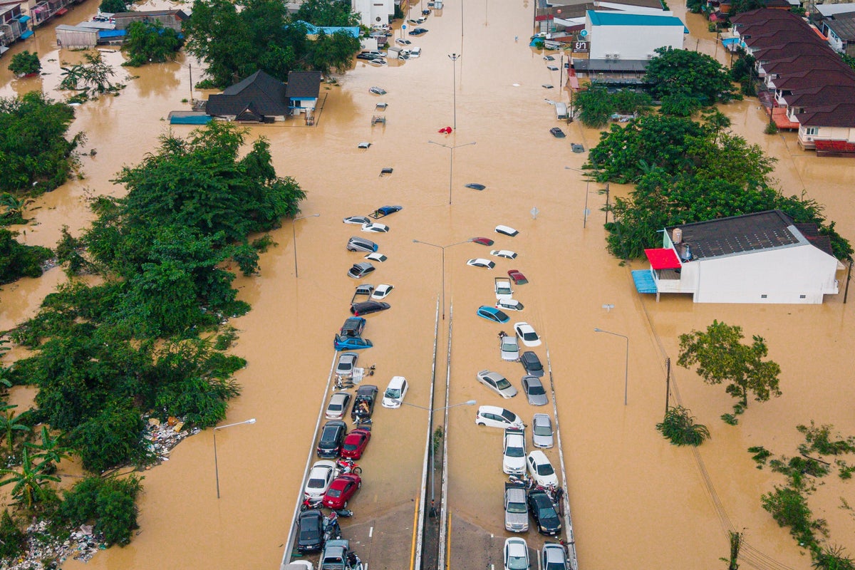 Families in southern Thailand perch on rooftops to escape flooding that has killed at least 33