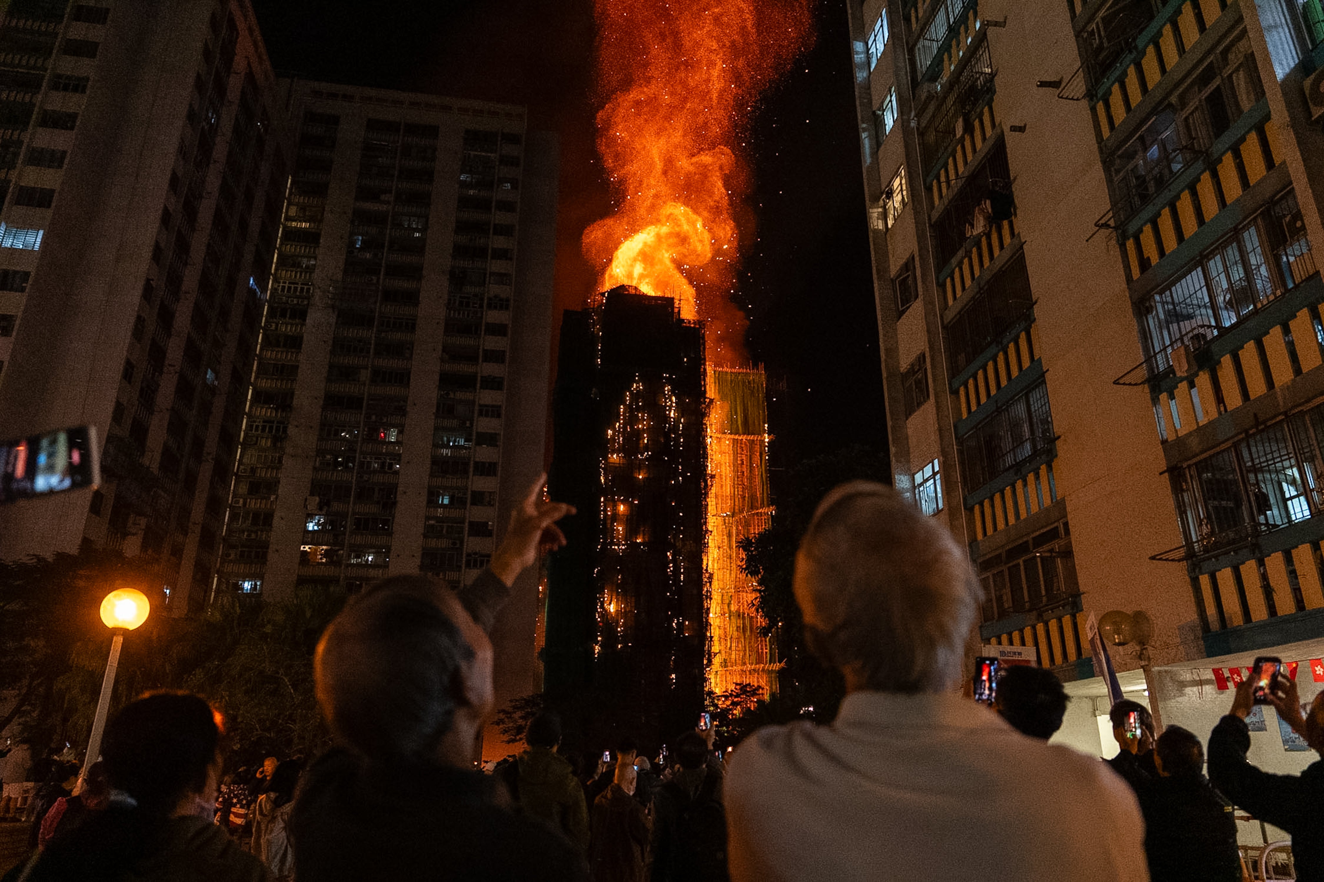 People look at flames engulfing a building after a fire broke out at Wang Fuk Court