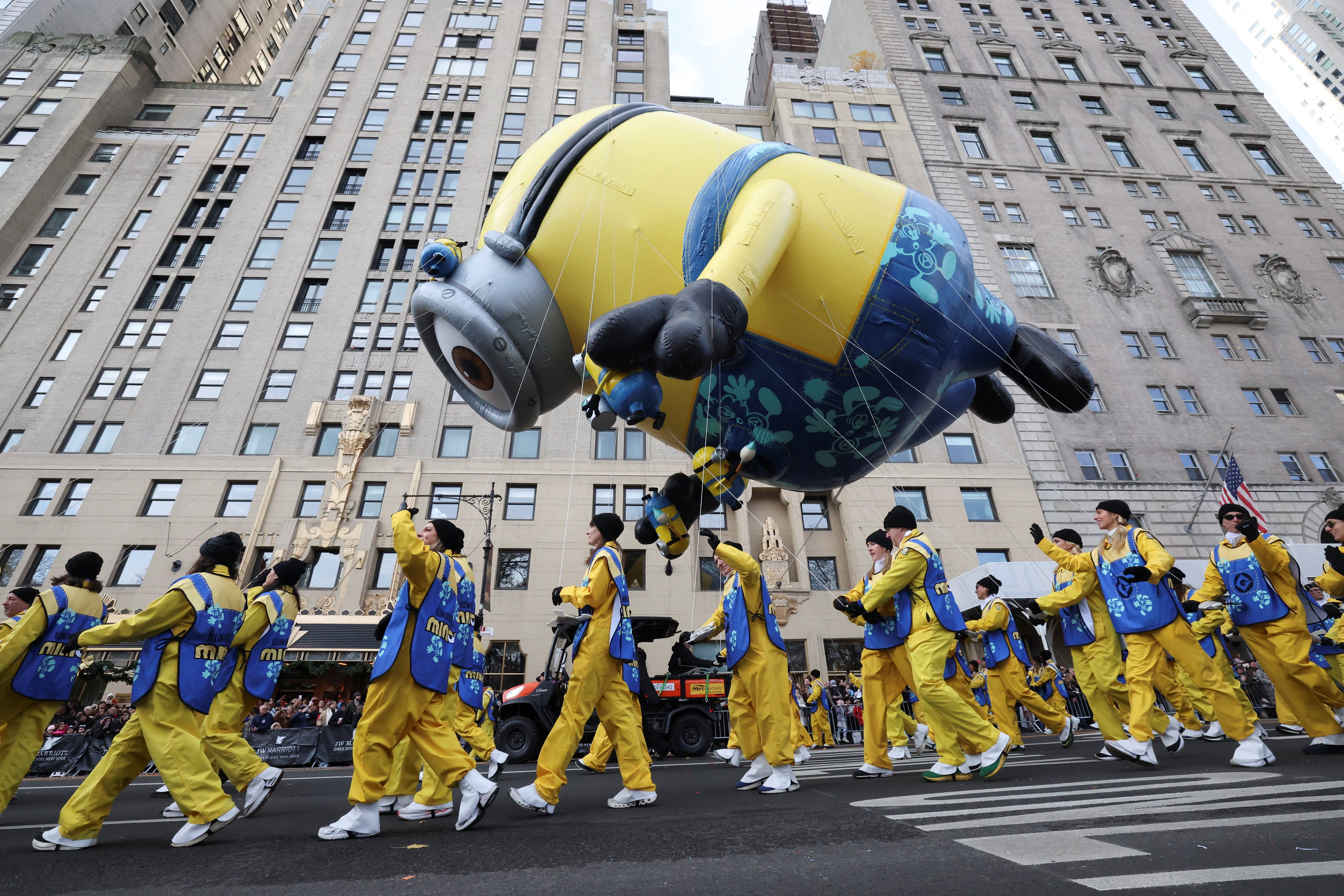 The Stuart the Minion balloon flies above performers at the 2025 Macy's Thanksgiving Day Parade