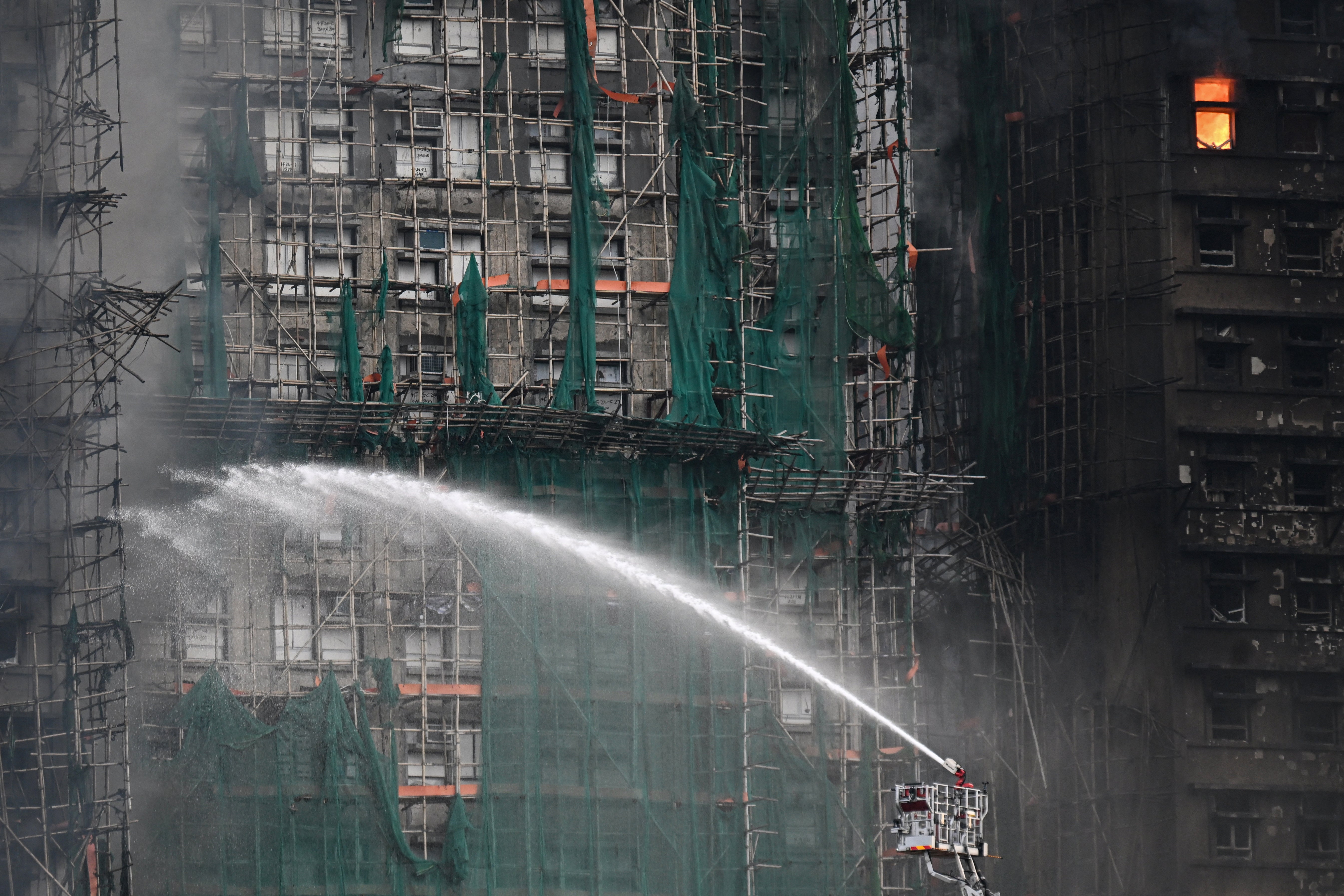 Firefighters spray water on flames as a major fire burns through several apartment blocks at the Wang Fuk Court residential estate in Hong Kong's Tai Po district