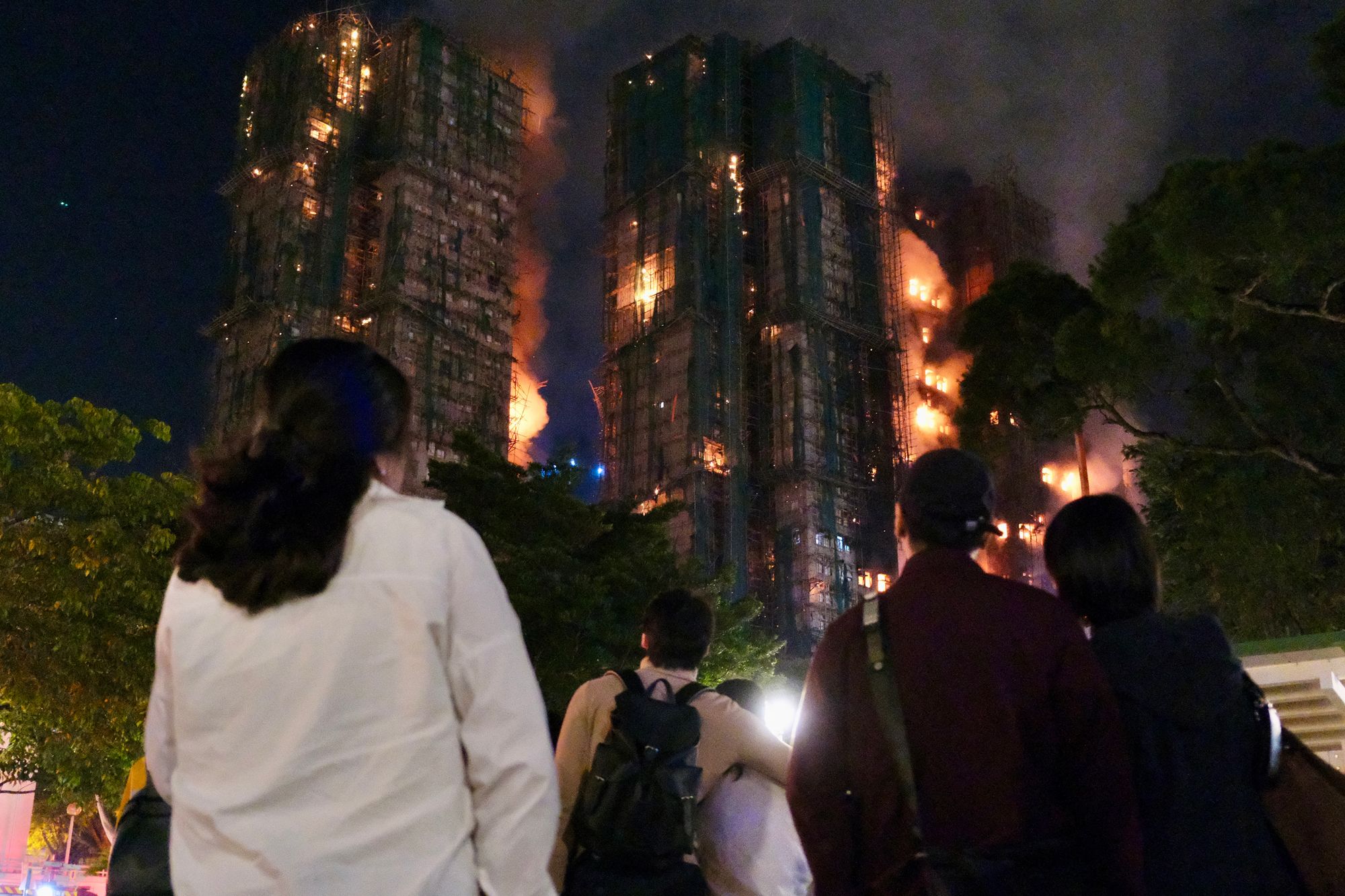 Pessoas observam fumaça espessa e chamas subindo durante um grande incêndio no bairro residencial Wang Fuk Court, no distrito de Tai Po, em Hong Kong.