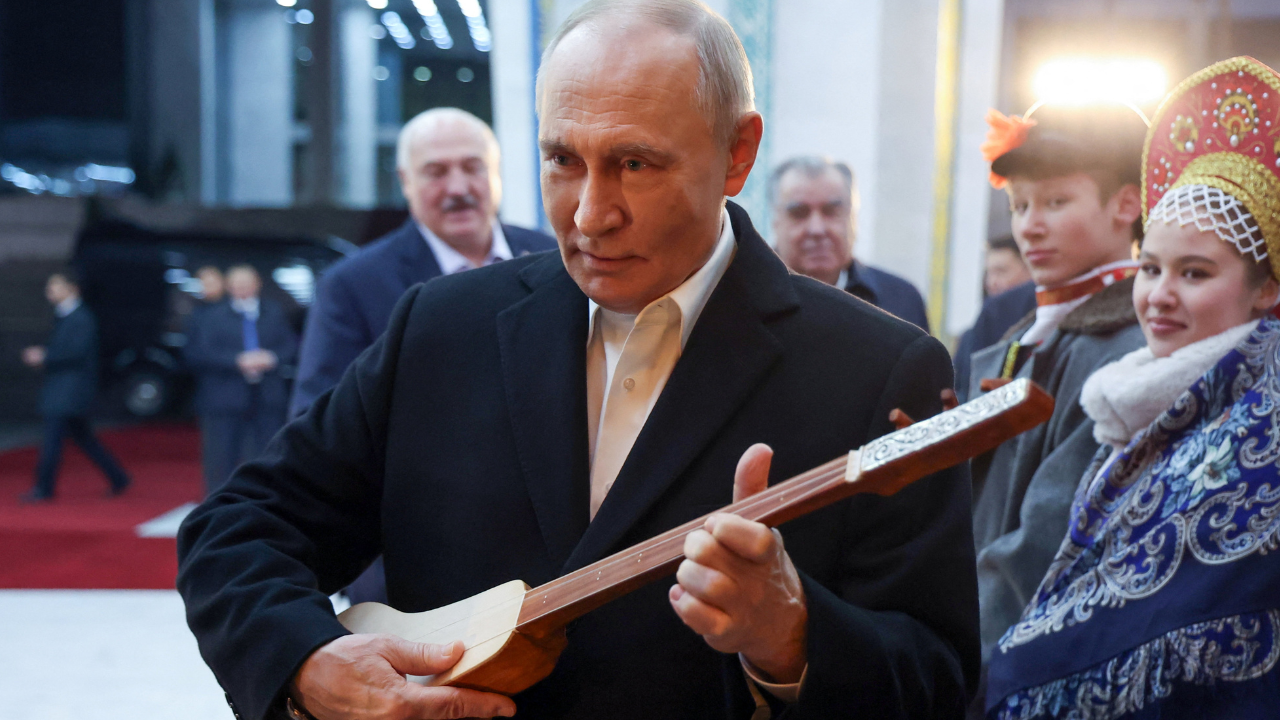 <p>Vladimir Putin holds a string instrument while visiting the Ala-Archa State Residence in Bishkek</p>