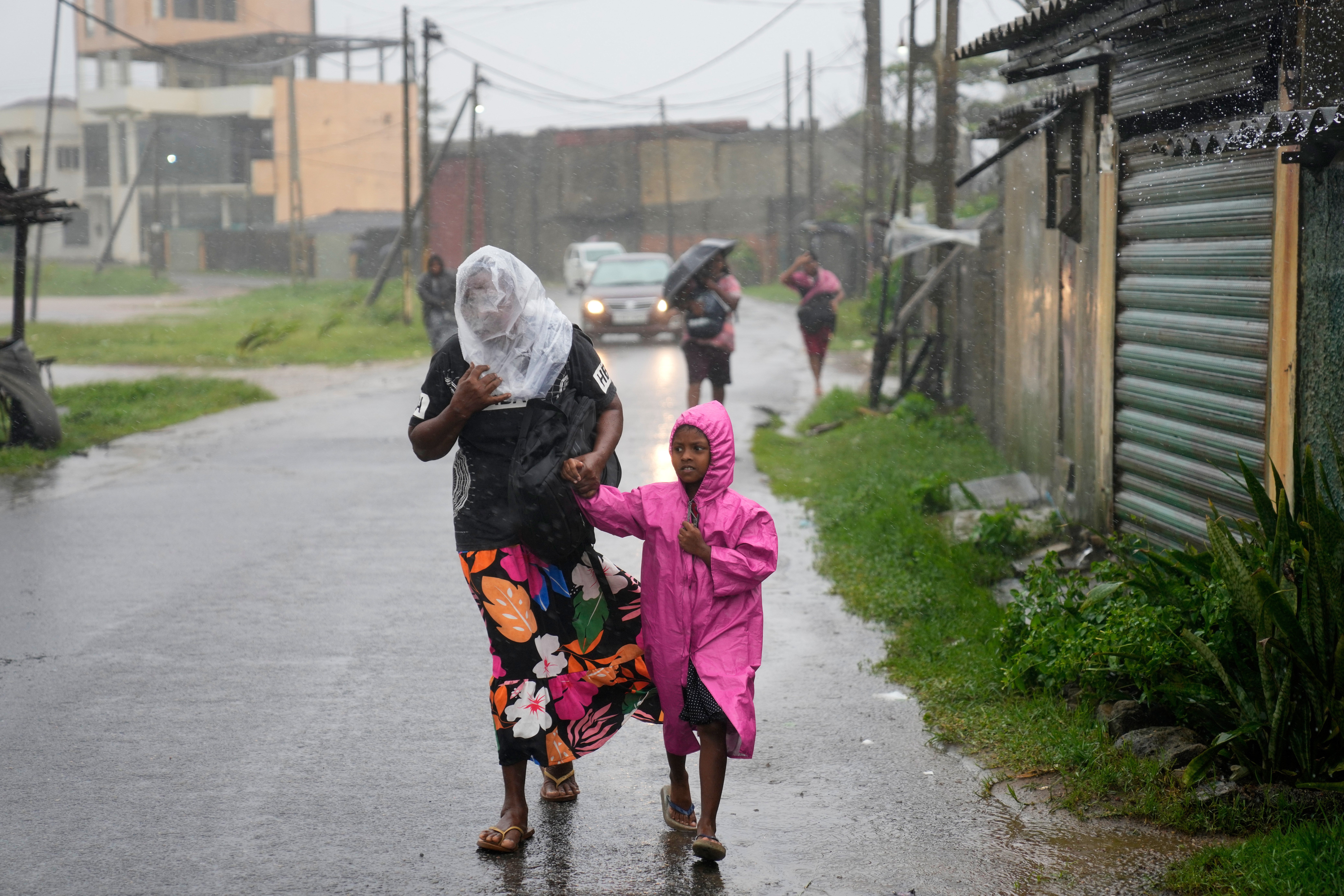 A woman and child walk under a downpour in Colombo, Sri Lanka