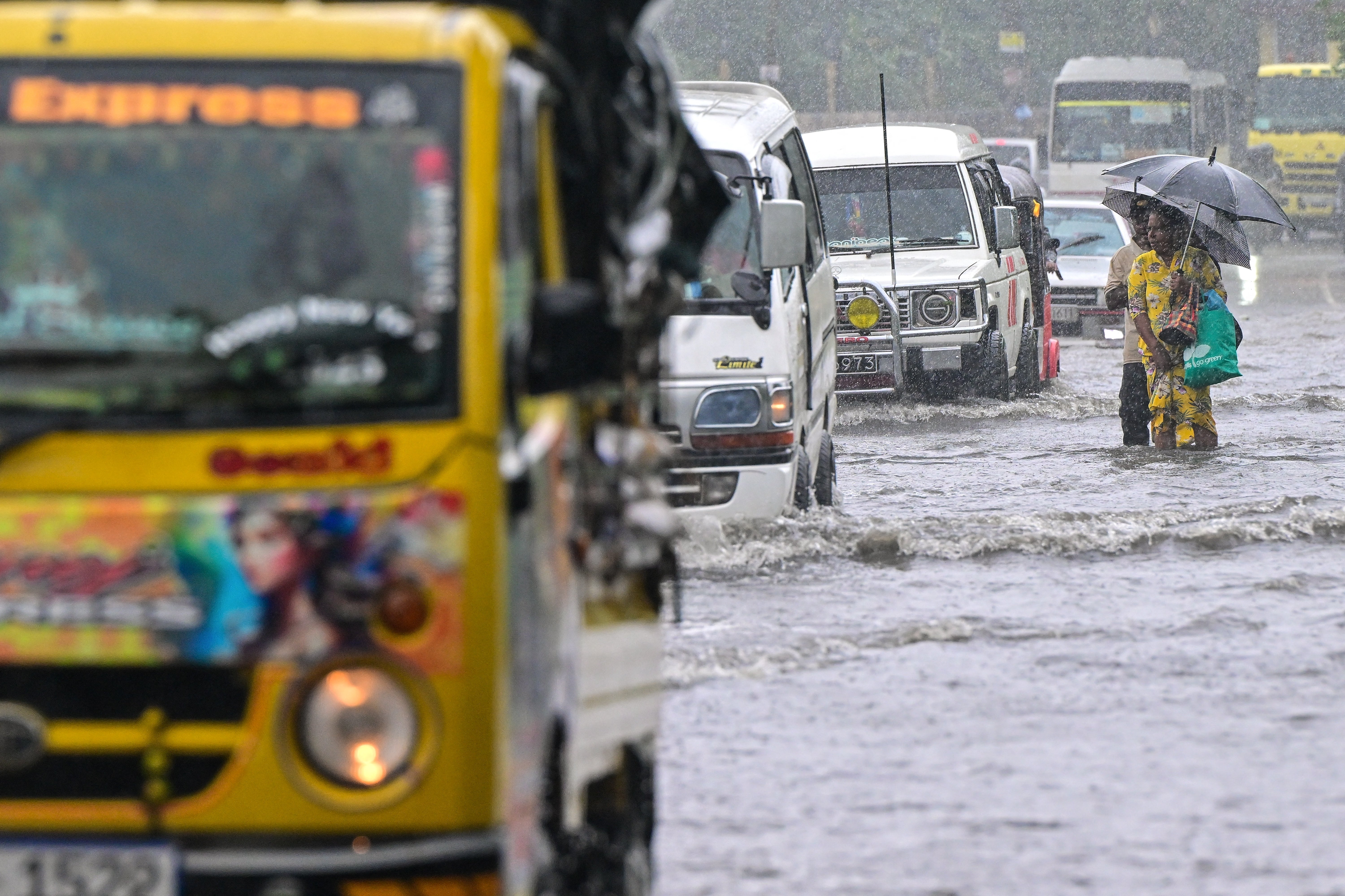 People wade through a flooded road in Biyagama, on the outskirts of Colombo
