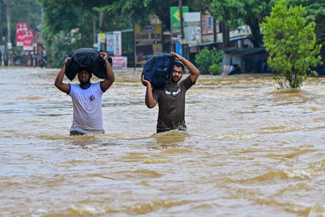 <p>People carrying belongings wade through a flooded road after heavy rainfall in Kaduwela on the outskirts of Colombo</p>