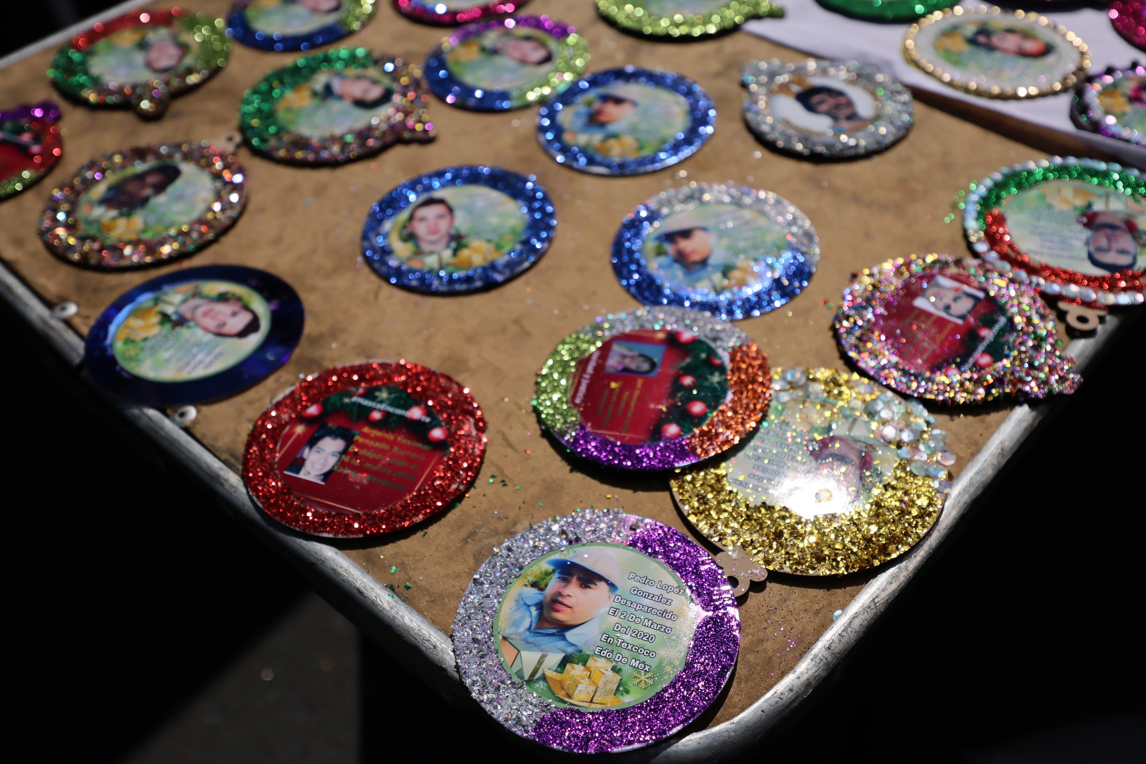 Christmas ornaments with photographs of the missing sit to dry before hanging on the Tree of Hope