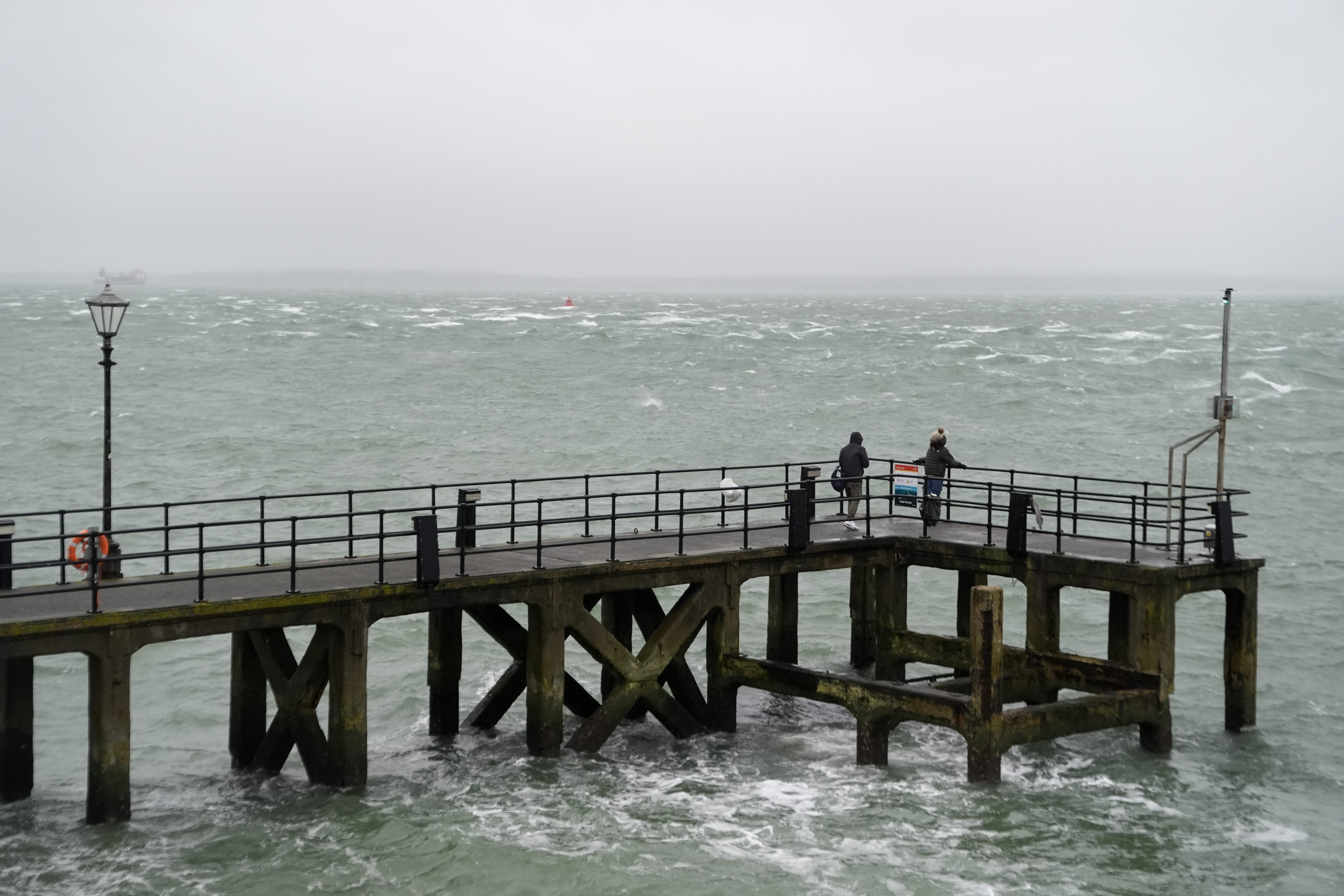 People walk along Victoria Pier in Portsmouth during a rain shower (Andrew Matthews/PA)