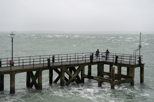 People walk along Victoria Pier in Portsmouth during a rain shower (Andrew Matthews/PA)