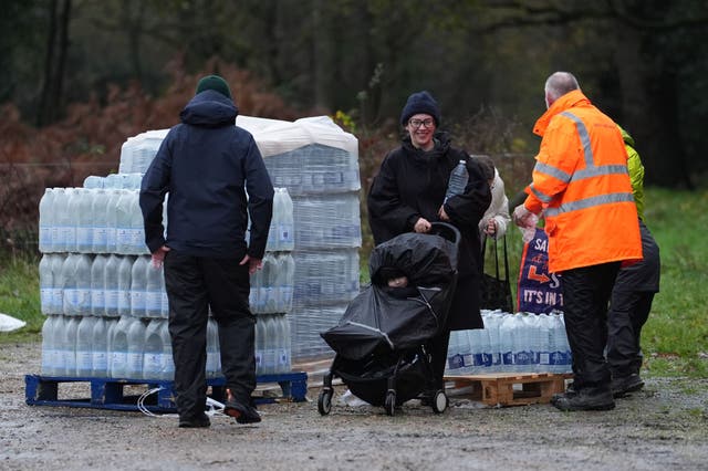 <p>Residents collect bottled water. As many as 23,000 homes and premises have been without it</p>