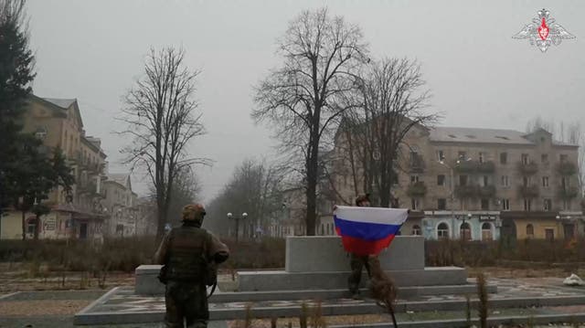 <p>A soldier holds a Russian flag in Pokrovsk</p>