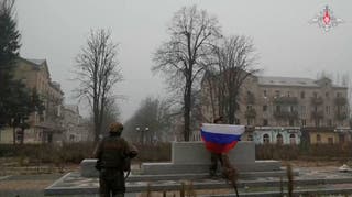 A soldier holds a Russian flag in Pokrovsk in Donetsk Region, Ukraine in this screengrab from video