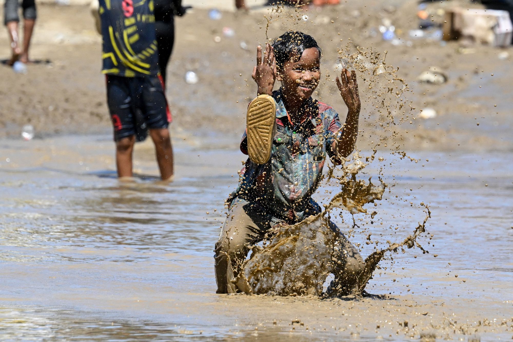 A child plays in the mudflow in the aftermath of flash floods in Meureudu, Pidie Jaya district in Indonesia's Aceh province on 30 November 2025
