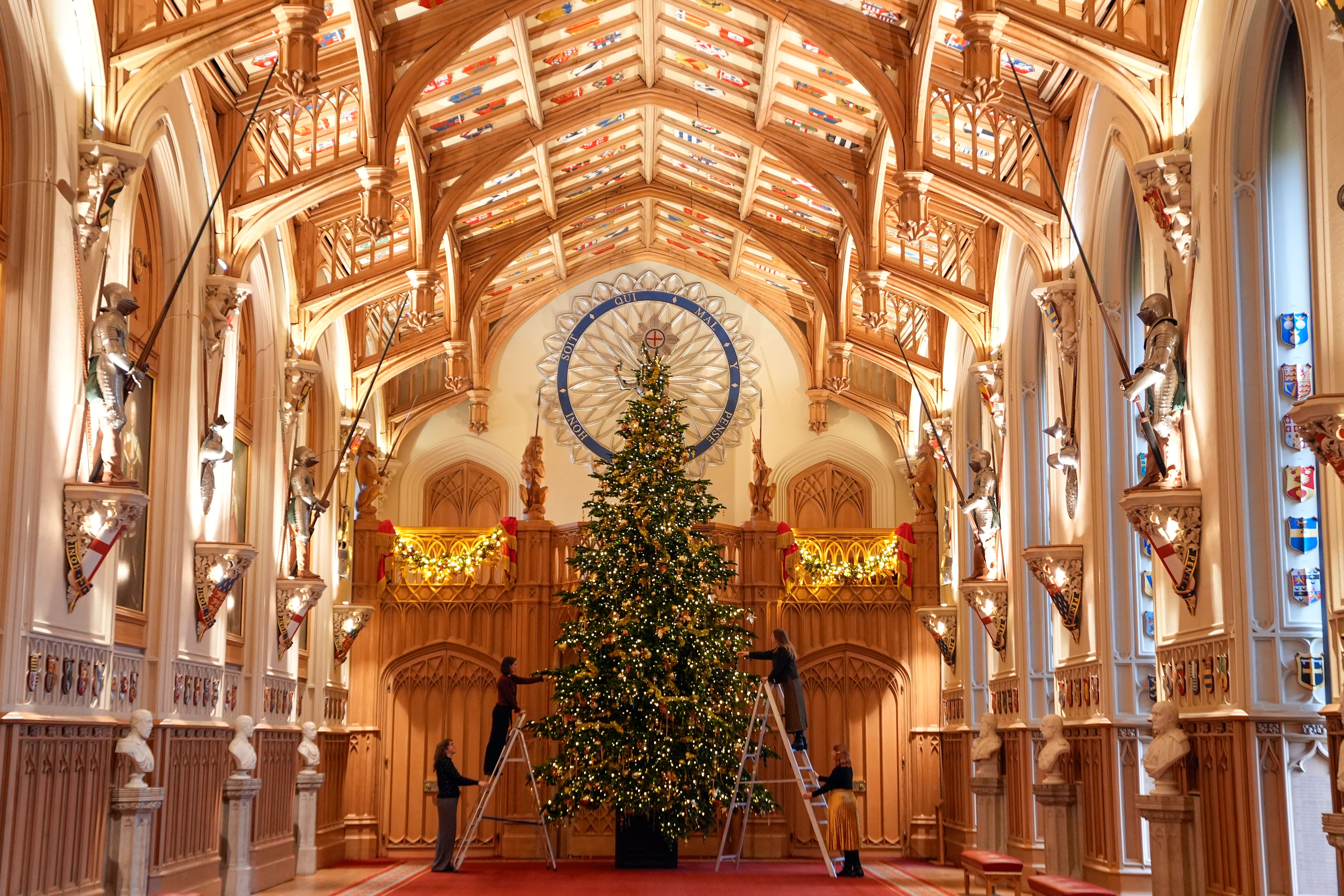 Royal Collection Trust staff adding the finishing touches to a Christmas tree in Windsor Castle’s St George’s Hall (Andrew Matthews/PA)