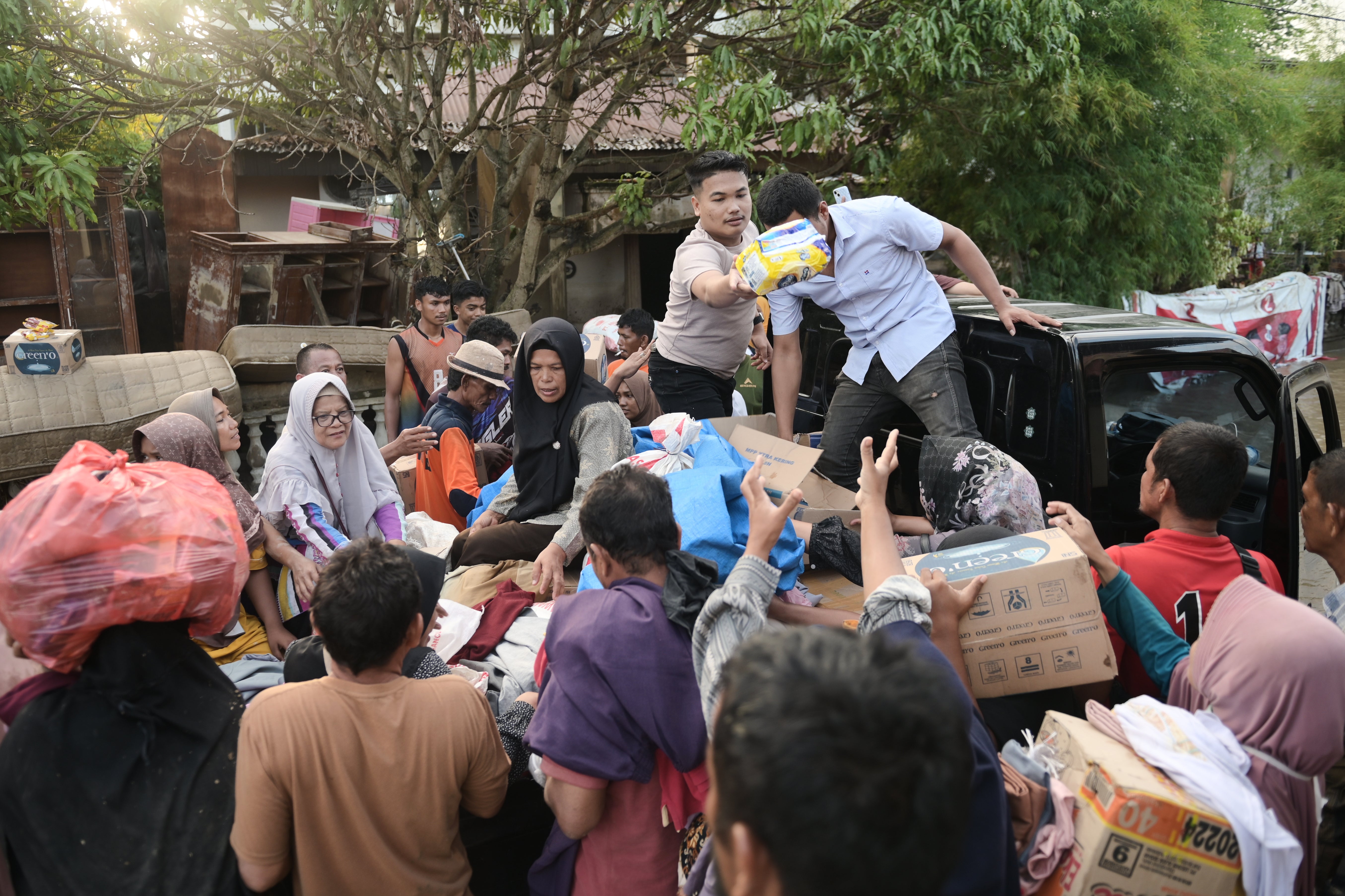 Volunteers distribute relief goods to survivors at a village affected by flash flood in Pidie Jaya, Aceh province, Indonesia