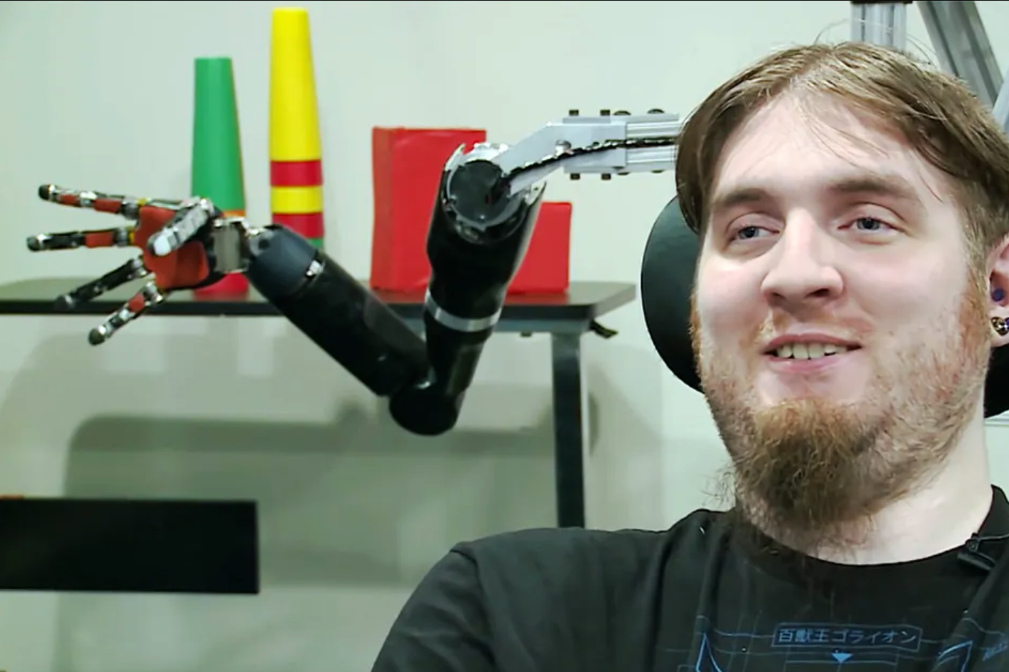 Brain computer interface pioneer Nathan Copeland pictured in front of a robotic arm in 2019