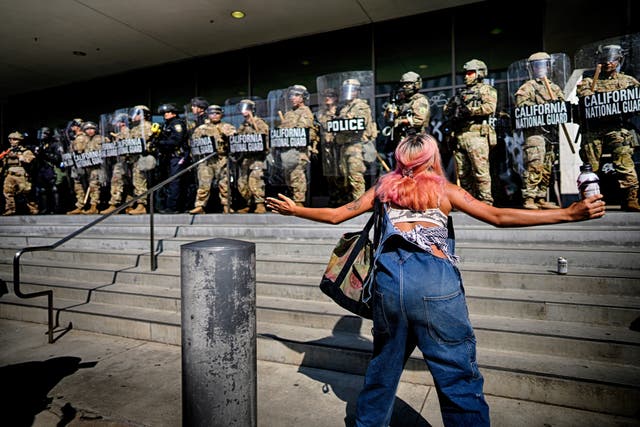 <p>A protester in front of a line of California National Guard members </p>