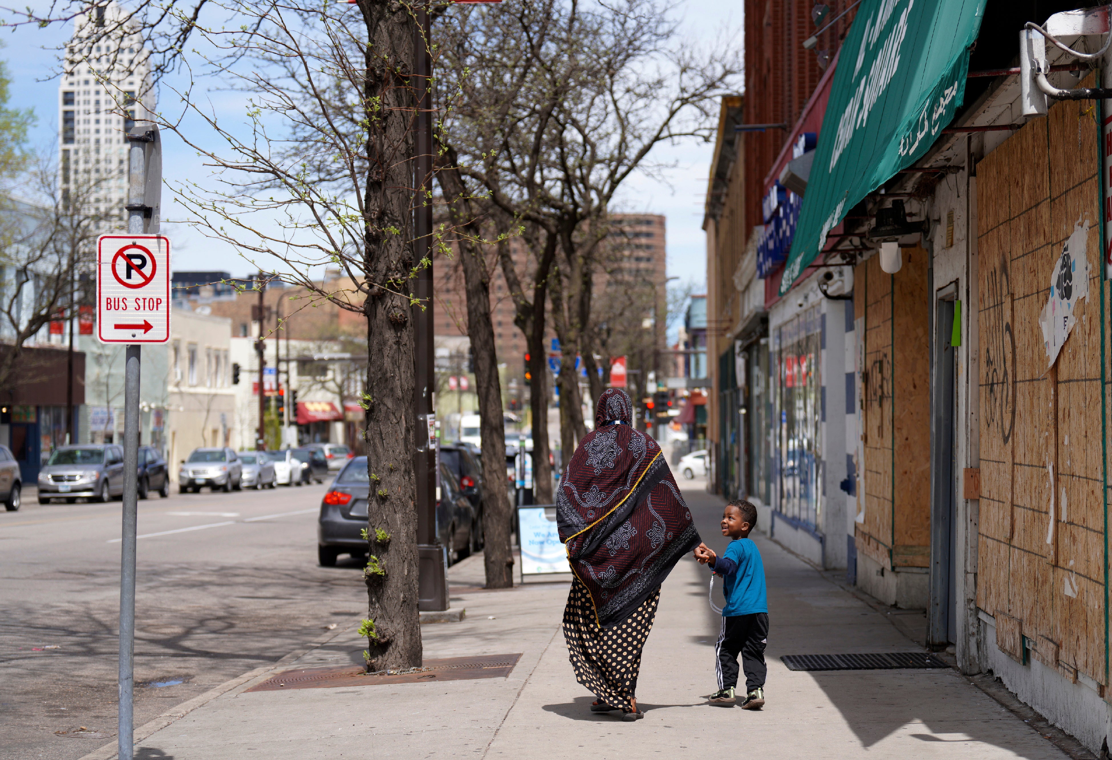 <p>A woman and a child hold hands as they walk down a street in the predominantly Somali neighborhood of Cedar-Riverside in Minneapolis on Thursday, May 12, 2022</p>