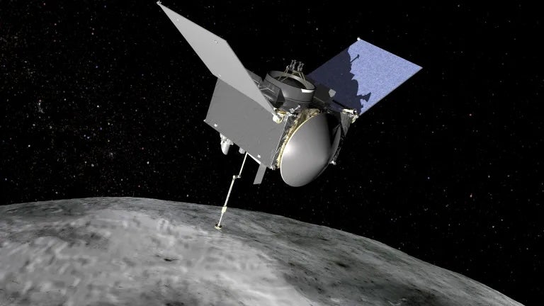 An illustrative image shows the OSIRIS-REx spacecraft flying over the ancient asteroid Bennu. Samples from the asteroid revealed hidden sugars that are essential for life on Earth