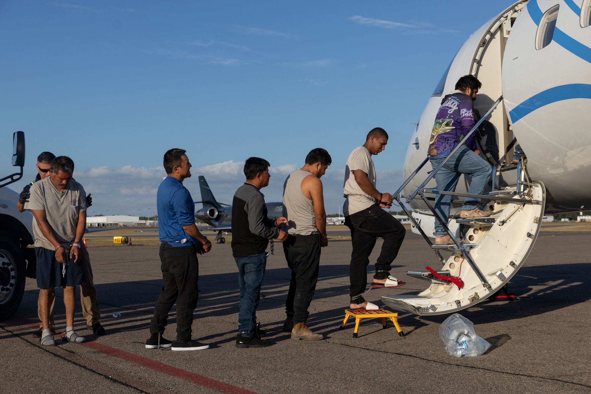 Shackled immigrants board a plane to be removed from the U.S. The Trump administration has branded self-deportations as a ‘dignified’ way to leave the U.S., compared to law enforcement action