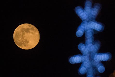 <p>This photograph taken on December 27, 2023 shows the last full moon of the year, also known as the 'Cold Moon', behind New Year's decorations in Skopje</p>