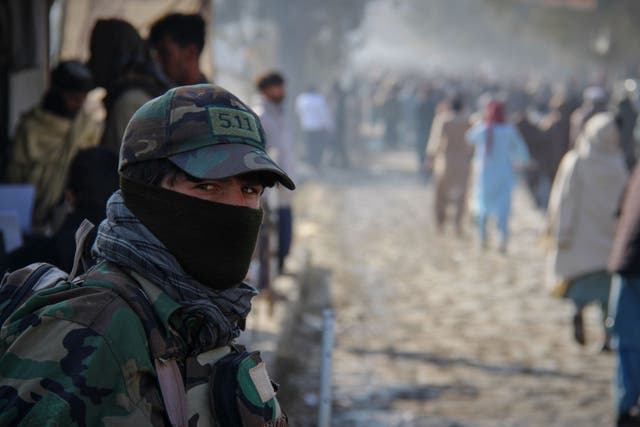 A Taliban policeman looks on as a crowd heads toward a stadium to attend the public execution carried out by Taliban authorities of a man sentenced by the Supreme Court for killing 13 members of a family, including children, earlier this year, in the eastern city of Khost, Afghanistan, Tuesday
