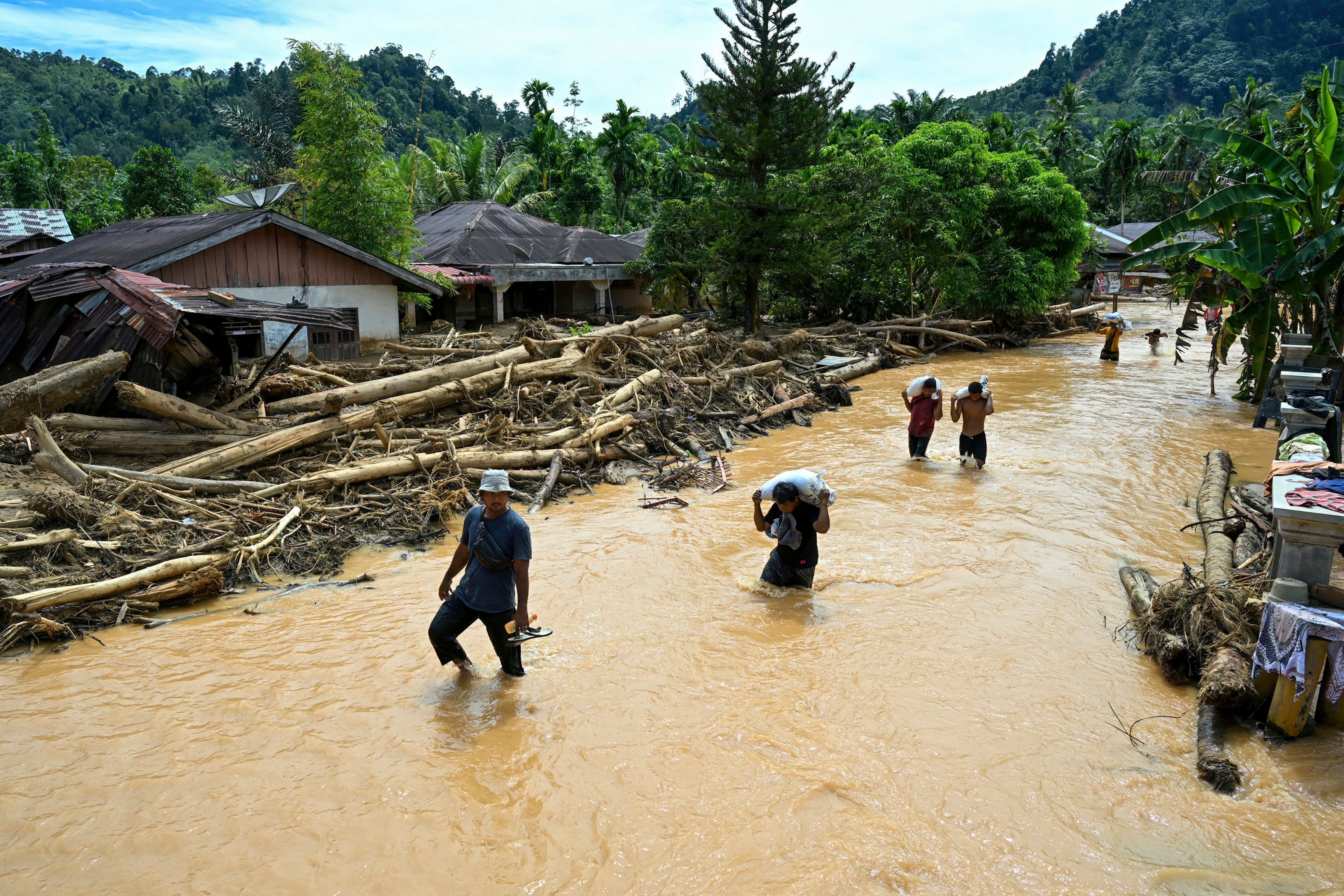 People wade through the floodwater in the aftermath of flash floods at Tukka village, Central Tapanuli, North Sumatra province, Indonesia
