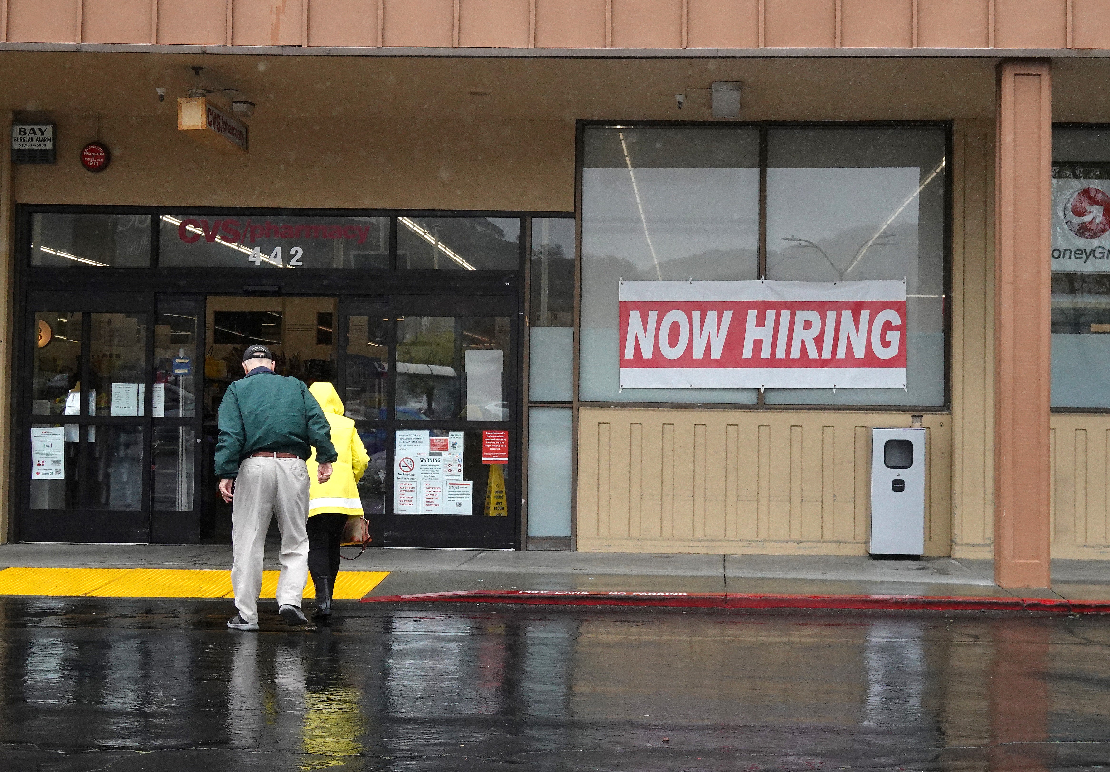 <p>People walk by a now hiring sign posted in front of a CVS store on April 07, 2023 in San Rafael, California</p>