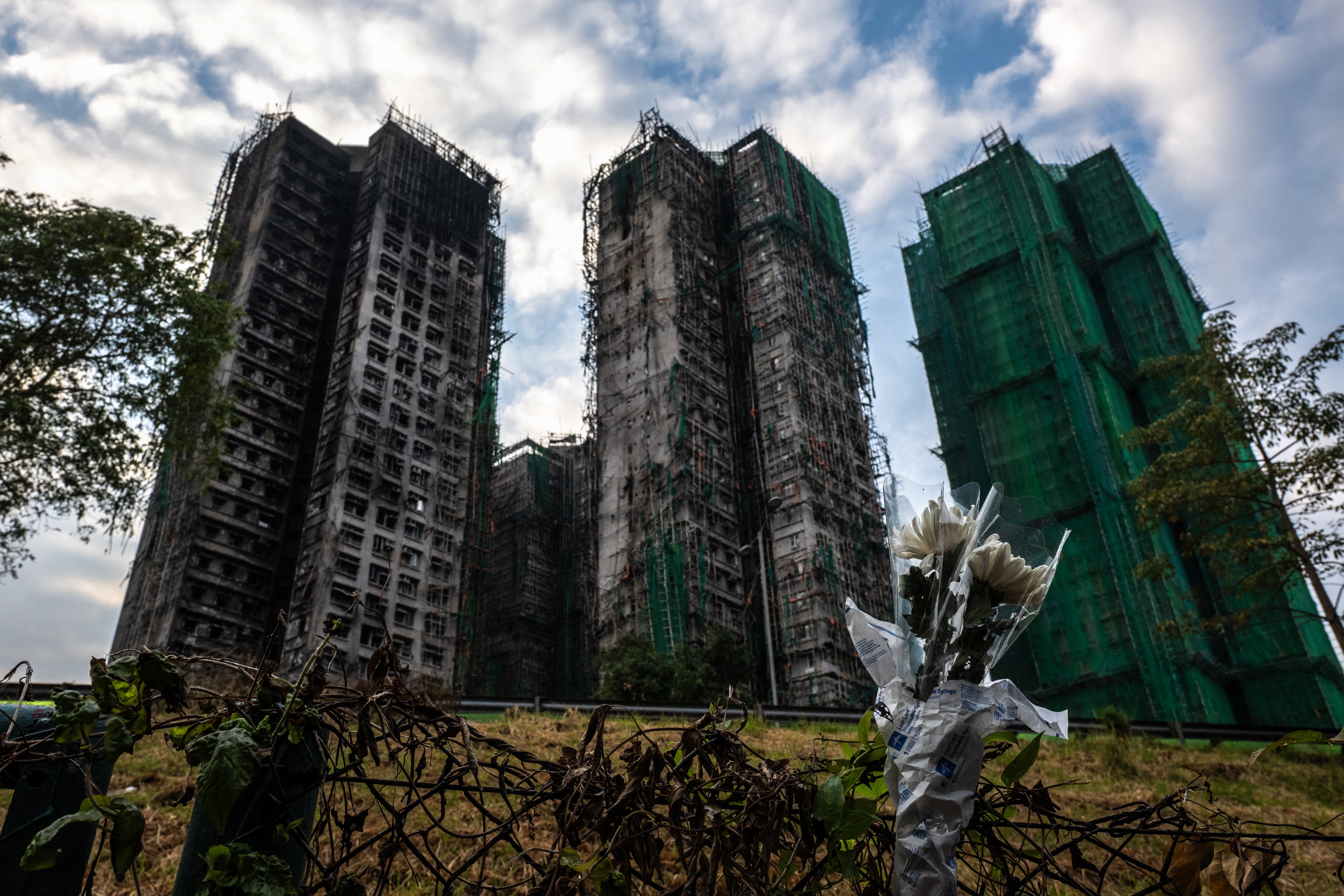 Flowers are seen in front of the Wang Fuk Court apartment blocks in the aftermath of the deadly 26 November fire in Hong Kong’s Tai Po district on 3 December 2025