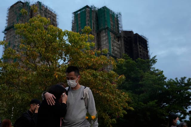 <p>A man consoles a woman near the Wang Fuk Court complex in Hong Kong on 2 December 2025</p>