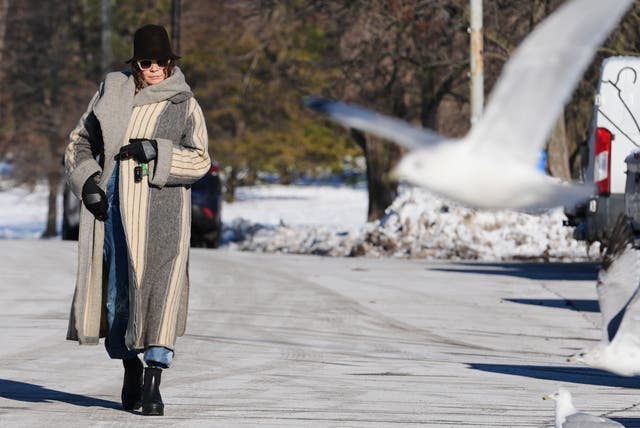 <p>A woman bundles up as she takes a walk during a cold weather day in the snow-covered at Lake Michigan, in Chicago, Thursday, Dec. 4, 2025</p>