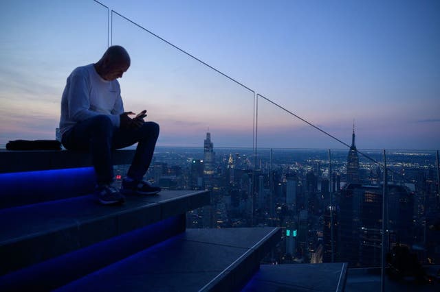 <p>A man looks at a mobile phone as he sits before the Manhattan skyline on June 10, 2021. A new study examined 10 of the leading credit card issuers in the country based on four categories and five tasks. In addition to Bank of America, the study included <a href="https://www.the-independent.com/news/american-express-lululemon-new-york-people-jpmorgan-chase-b2829060.html">American Express</a>, Barclays US, Capital One, Chase, Citibank, Discover, PNC, US Bank, and Wells Fargo.</p>
