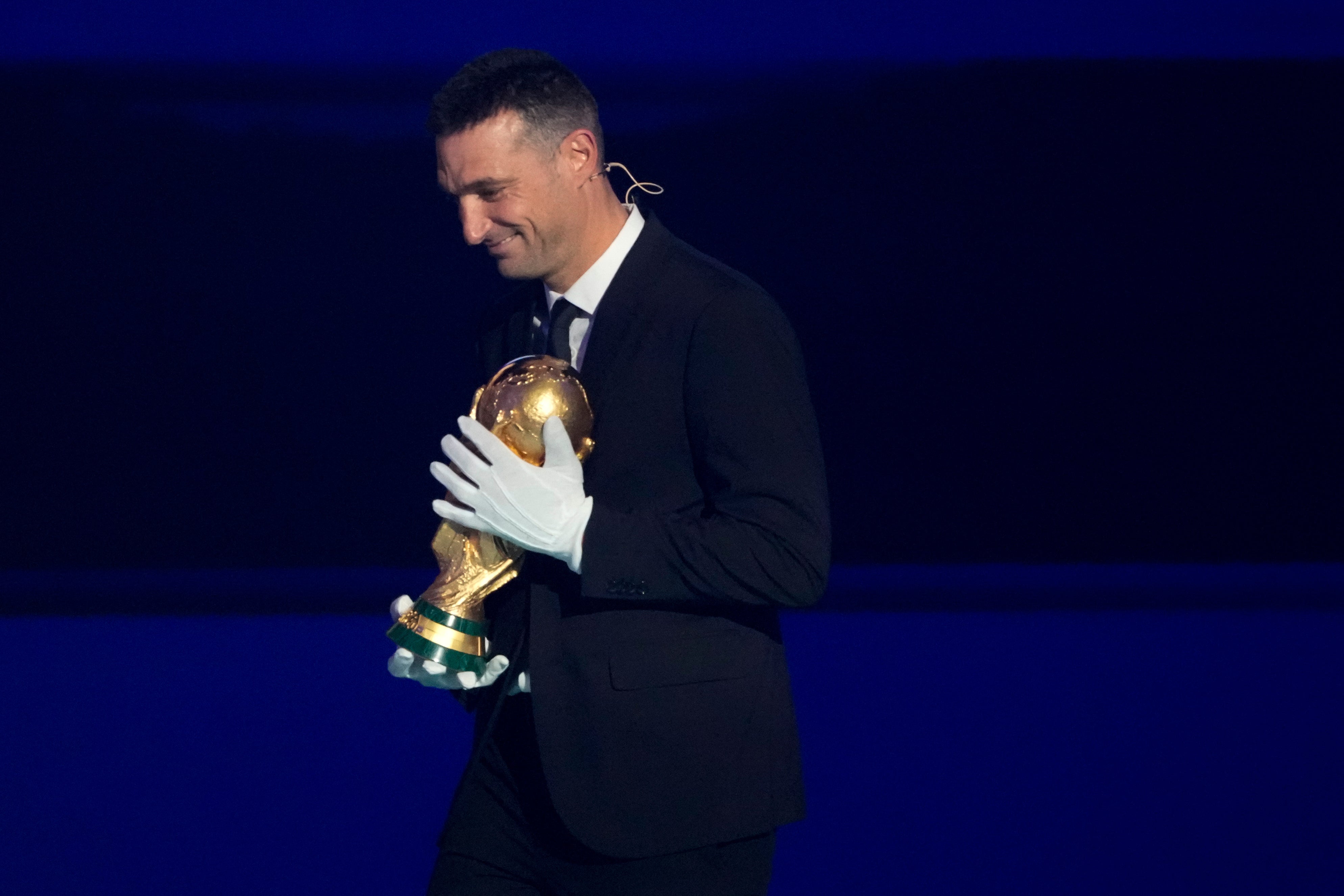 <p>Lionel Scaloni brought the World Cup trophy onto stage wearing gloves</p>
