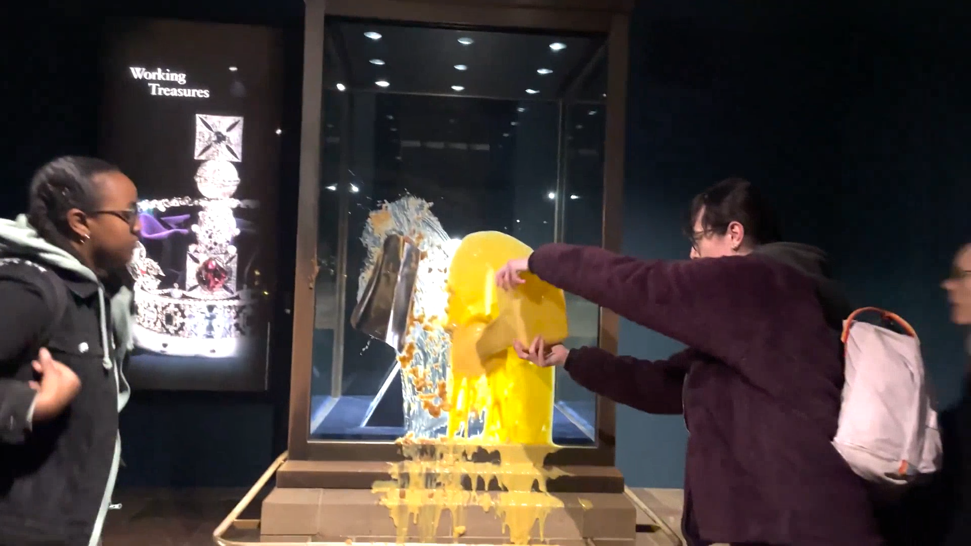A protester repeatedly poured a tub of bright yellow custard on the front of the case