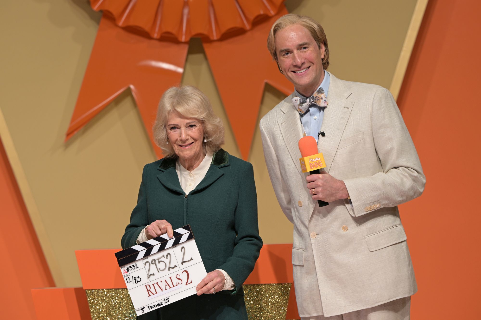 <p>Queen Camilla with actor Oliver Chris as she holds a clapper board during a visit to the set of the series Rivals in Bristol, to celebrate British television production, youth opportunity in the creative industries, and the legacy of her friend, the author Dame Jilly Cooper. Picture date: Monday December 8, 2025. PA Photo. Photo credit should read: Anthony Upton/PA Wire</p>