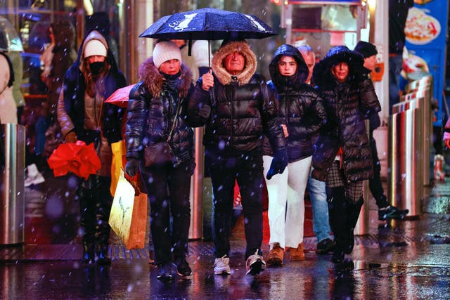 <p>Snow and rain falls as people walk through a dark and stormy Times Square in New York City in January 2024. Many people take vitamin D supplements during the winter months, but knowing how much to take is crucial</p>