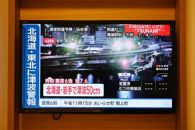 <p>A tsunami warning flashes over live footage of a waterfront area, on a television screen in Sapporo, in Japan's northern Hokkaido prefecture on December 9, 2025</p>