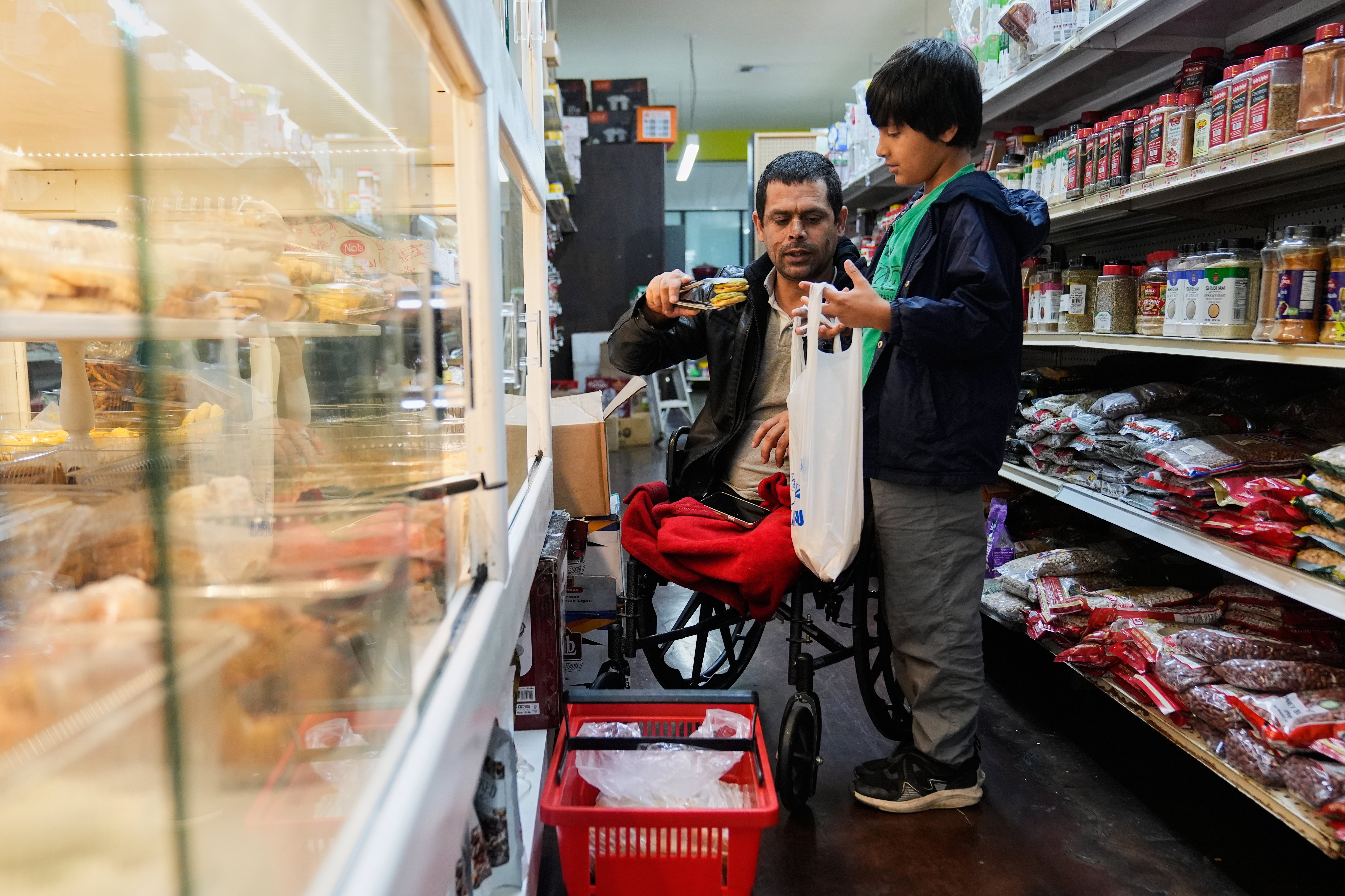 <p>Abdul Salam, center, and his son Ahmad Sodais shop for sweet treats inside of an Afghan grocery store in Carmichael, Calif., Friday, Dec. 5, 2025. (AP Photo/Godofredo A. Vásquez)</p>