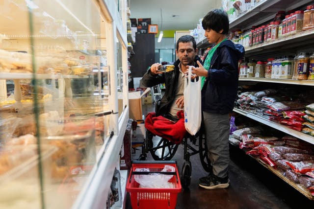 <p>Abdul Salam, center, and his son Ahmad Sodais shop for sweet treats inside of an Afghan grocery store in Carmichael, Calif., Friday, Dec. 5, 2025. (AP Photo/Godofredo A. Vásquez)</p>