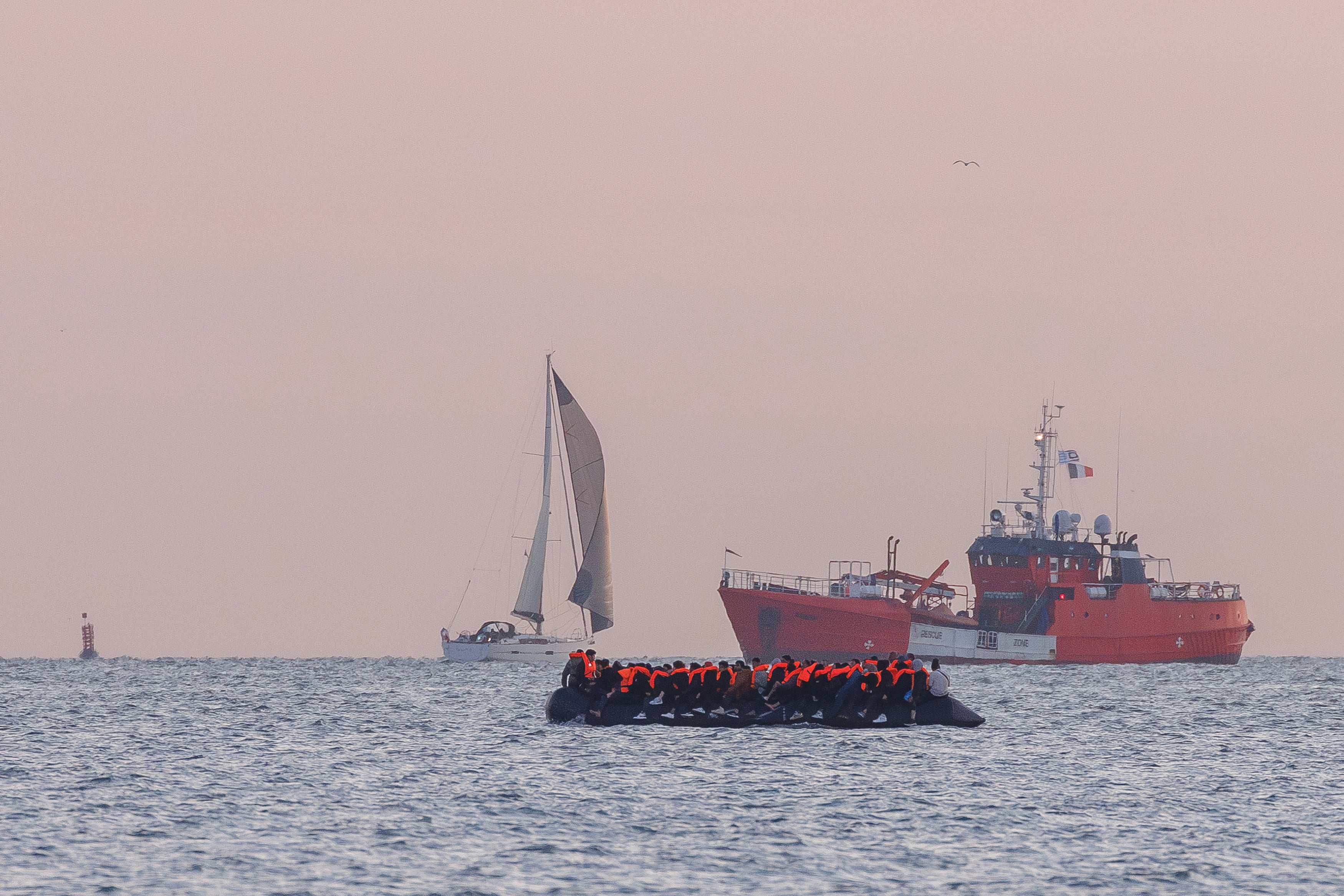 A search and rescue vessel shadows a small boat carrying migrants in Gravelines, France, in August