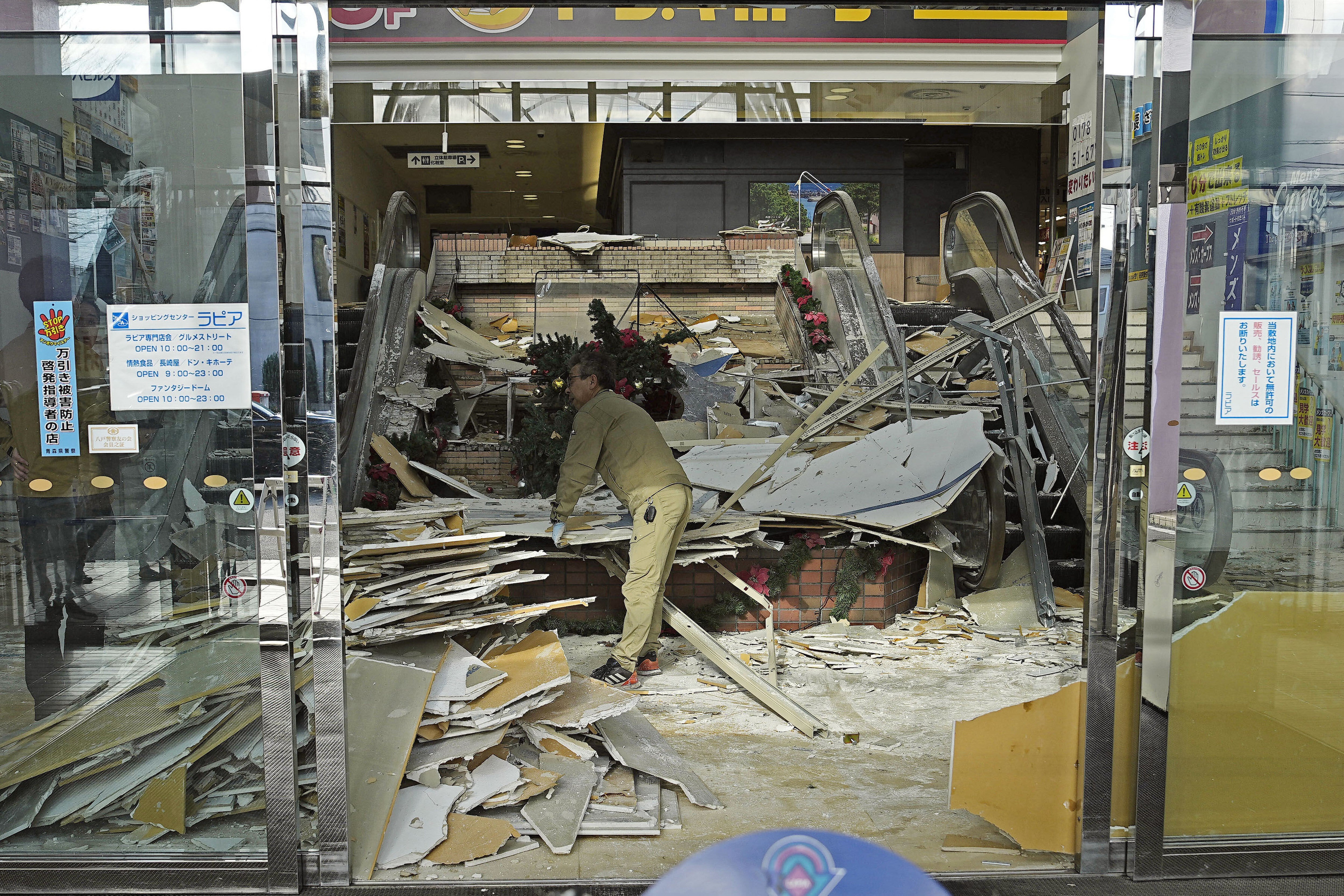 A man clears the debris from a powerful earthquake at a commercial facility in Hachinohe, Aomori prefecture, northern Japan Tuesday, 9 December 2025