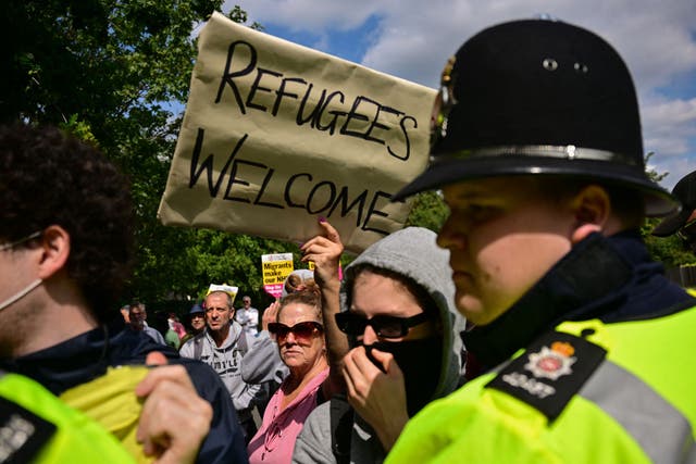 <p> A demonstrator holds a placard reading 'Refugees Welcome' during a counter protest to an anti-immigration protest outside the Sheraton Four Points hotel, believed to be housing asylum seekers, in Horley, south of London, on August 23, 2025. </p>