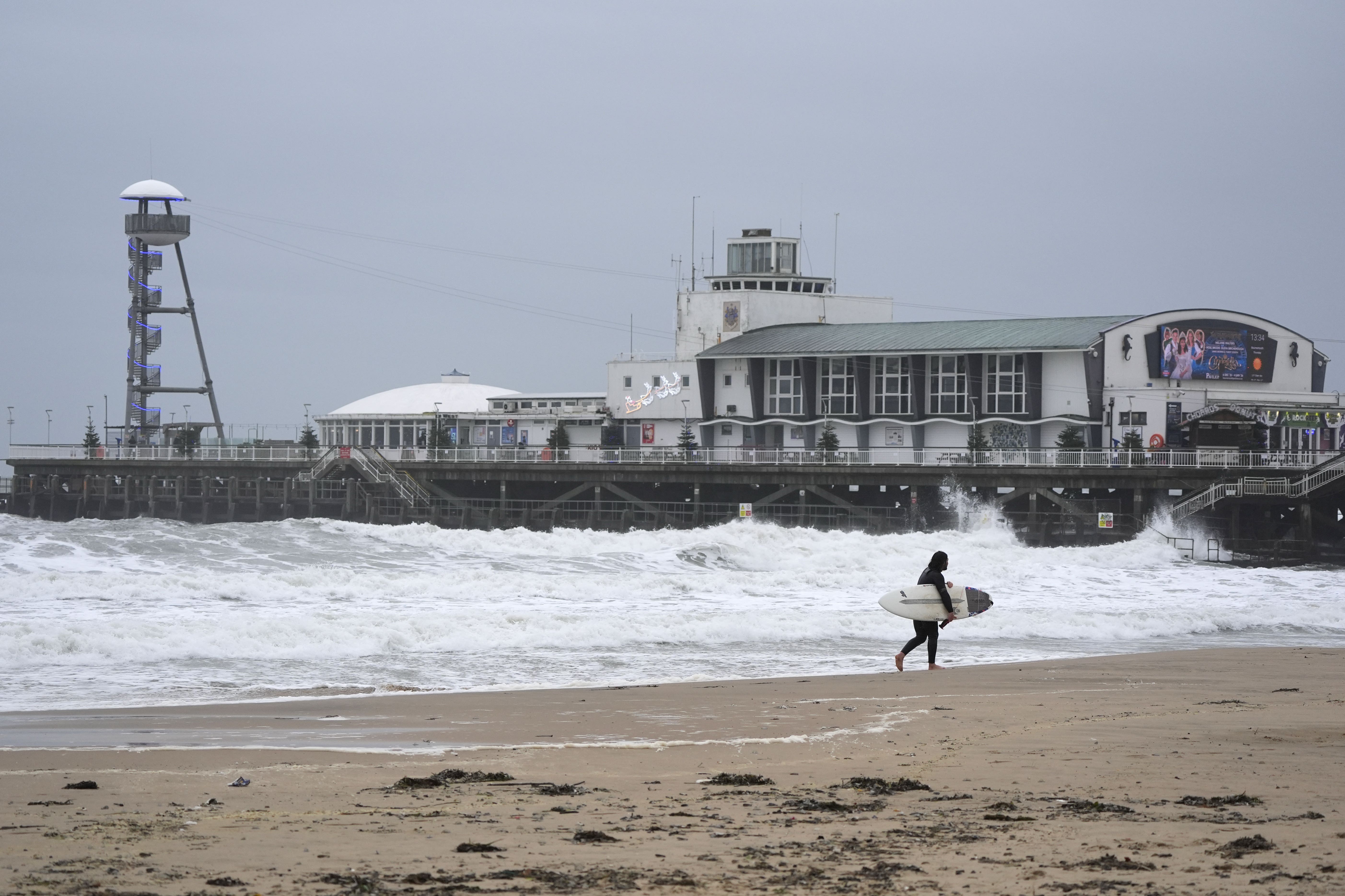 A surfer makes their way out of the sea on Bournemouth beach in Dorset (Andrew Matthews/PA)